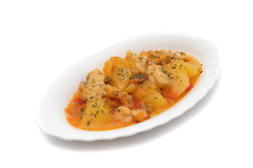 Potato stew with cod, shrimp and parsley on top, served on a white plate. Isolated on white background, Selective focus. Spanish food.