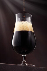 Stream of dark stout pours into a beer glass. Shallow depth of field