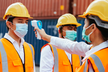 asian man workers wearing face mask checking fever by digital thermometer before entering the work for protecting from covid, covid-19 or coronavirus pandemic on construction site. selective focus.