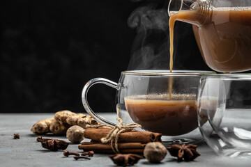 Glass cup of traditional indian masala chai tea with milk and spices on gray background. banner, menu, recipe place for text, top view