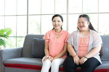 down syndrome teenage girl with mother looking something on sofa