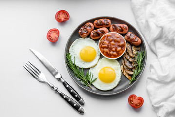 Full english breakfast with bean, fried eggs, roasted sausages, tomatoes and mushrooms