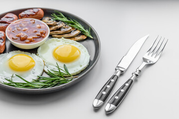 Full english breakfast with bean, fried eggs, roasted sausages, tomatoes and mushrooms