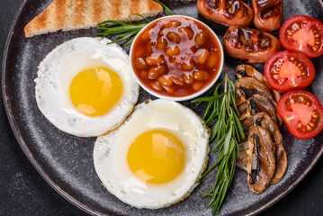 Full english breakfast with bean, fried eggs, roasted sausages, tomatoes and mushrooms