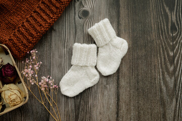 Small woolen baby socks, on dark wooden background