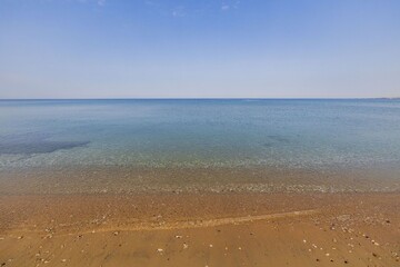 Beautiful nature landscape view.  Coastline merging to sea surface and blue sky on horizon. Greece. 