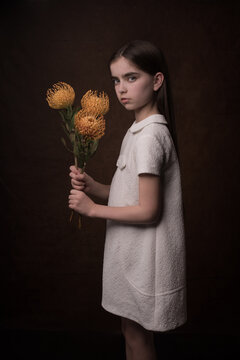 girl in white dress holding yellow flowers in classic studio portrait