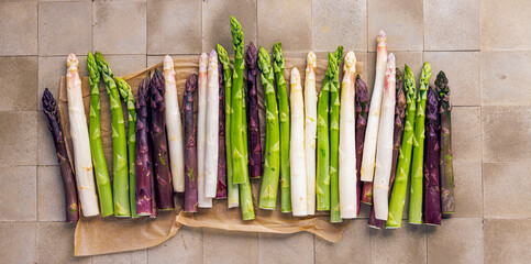 Green, white and purple asparagus on a kitchen background