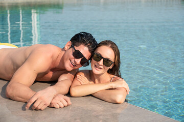 Happy young Caucasian couple in pool and woman and smiling together. A couple with romantic moments with copy space.