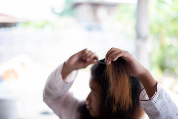 Damaged Hair, frustrated asian young woman, girl hand in holding brush splitting ends messy while combing hair, unbrushed dry long hair. Health care beauty concept.