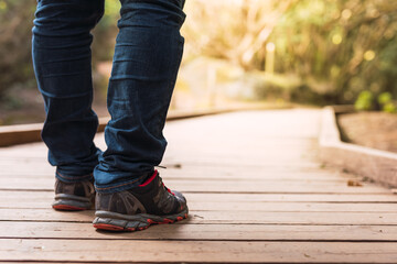 Close-up shot of a person's boots walking along a wooden path in the bush