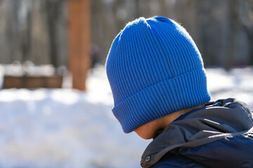 Teen boy pulled blue knitted hat over his eyes to hide his face from the camera lens, family...
