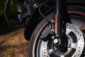 front fork of a motorcycle with a front wheel, brake disc, brake cylinder. Close up. Soft focus