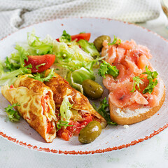 Breakfast. Omelette roll with tomatoes and sandwich with salmon on white plate.  Lunch.