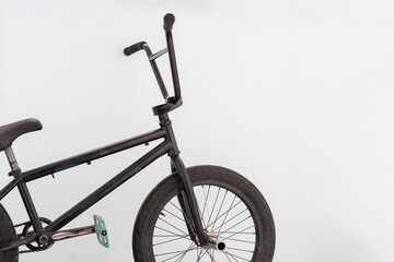 a black bmx bike standing near the wall, extreme sports equipment