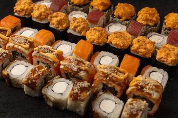 Japanese cuisine, sushi and fresh fish rolls on black background