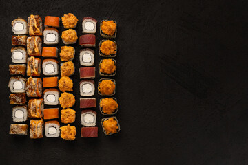 Japanese cuisine, set of fresh fish rolls on a black background with copy space