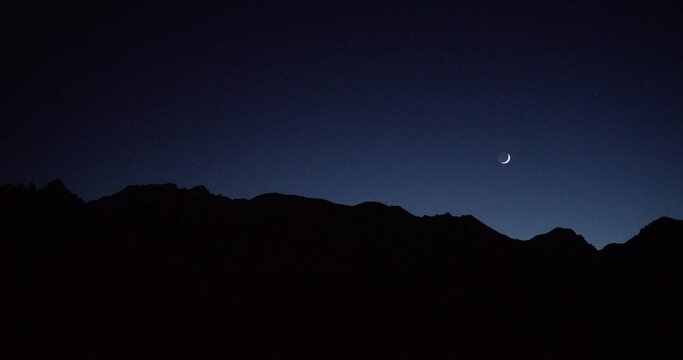 Night sky with moon above mountain silhouettes in Alabama Hills, California