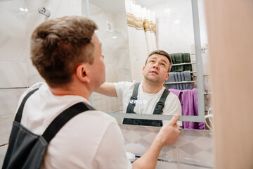 repairman hangs a modern electronic bathroom mirror.