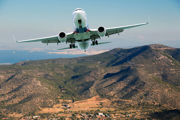 Fototapeta na wymiar Passenger jet plane flies over the mountain lanscape. Aircraft front view.