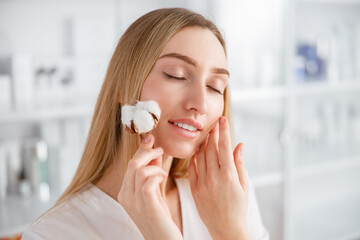 Young woman with cotton plant standing in beauty salon