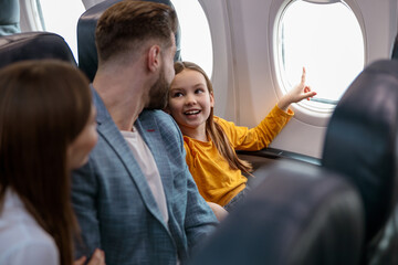 Little girl with parents traveling on airplane