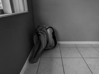 A young girl is sitting on the floor in a room. Stop human trafficking. Soft focus
