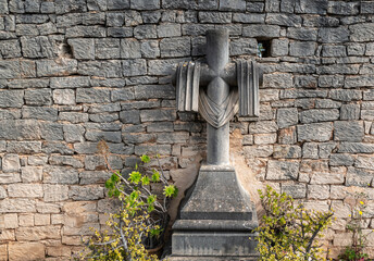 schönes Grabkreuz vor einer Mauer  auf einem Friedhof der Insel Mallorca