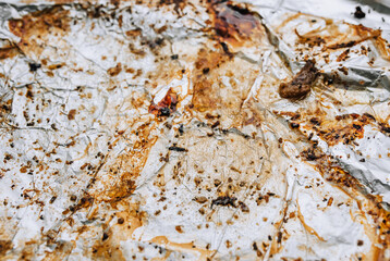 Background, texture, top view of dirty, greased, after cooking a meat dish, crumpled foil. Photograph of food preparation.