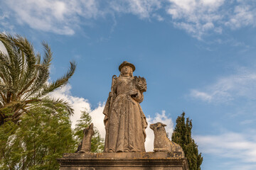 Fototapeta na wymiar Eine Hirtin mit einem Schaf auf einem Grabstein auf einem Friedhof der Insel Mallorca