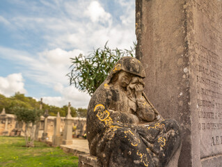 Fototapeta na wymiar Eine Frau in tiefer Trauer neben einem Grabstein auf einem Friedhof der Insel Mallorca