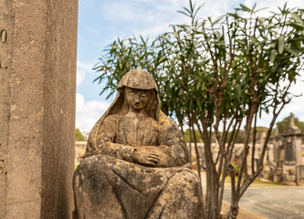 Eine Frau in tiefer Trauer  neben einem Grabstein auf einem Friedhof  der Insel Mallorca