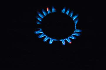 Burning blue industrial methane gas in the form of fire on a stove close-up.