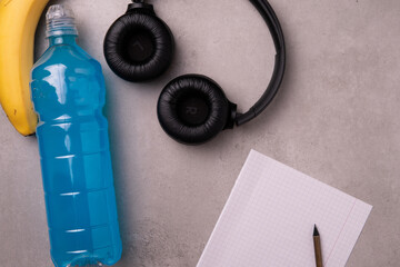 blue isotonic to replenish electrolytes and energy in a plastic bottle on a concrete background piece next to a of blank white paper