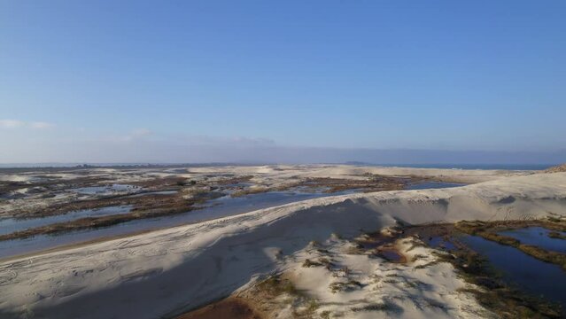 Drone footage of small ponds created by rain in the middle of dunes