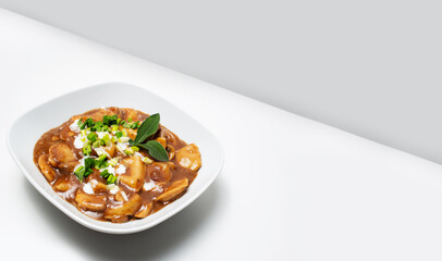 Vegan food. Homemade dumplings in gravy, in bowl on white table with copy space.