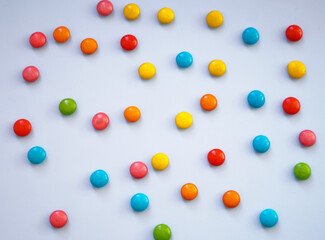 Sweet chocolate multi-colored dragees. Blue background.