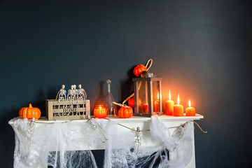 Halloween home decoration. Plastic toy skeletons in a wooden box on a fireplace against a dark blue...