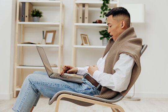 Man Sitting In A Chair In A Room With A Laptop On His Lap Gray Background