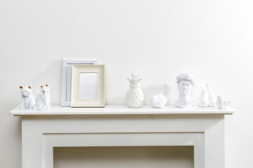 Photo frame with place for text, ceramic figurines of birds, David's head, fox, bear, pears on the fireplace. Office decoration. Copy space