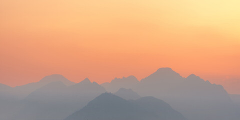 Fototapeta na wymiar bright sunset or sunrise sky with misty mountains