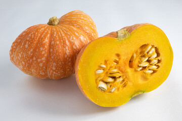 Ripe and fresh pumpkin, cut in half, with exposed seeds. On white background
