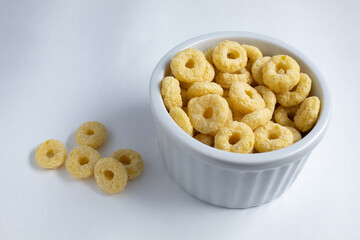 Delicious yellow loops breakfast cereal, served in white ramekin, with a few units dropped to the side