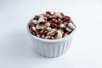 Raw fava beans in white, brown and red colors, inside a ramekin, ready to be prepared. Nutritious and healthy food