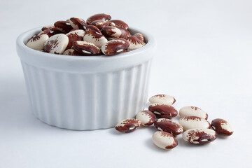 Raw fava beans in white, brown and red colors, inside a ramekin, ready to be prepared. Nutritious and healthy food