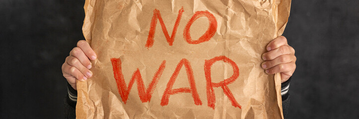 Child holding a banner with the inscription No war. Close-up. No war, stop the war, peace