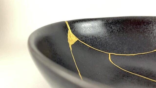 The making of kintsugi, artisan making kintsugi process. Slow motion cinematic video. Black Kintsukuroi bowl.
Closeup isolated.