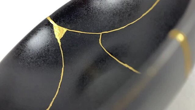 The making of kintsugi, artisan making kintsugi process. Slow motion cinematic video. Black Kintsukuroi bowl.
Closeup isolated.