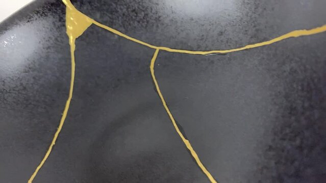 The making of kintsugi, artisan making kintsugi process. Slow motion cinematic video. Black Kintsukuroi bowl.
Closeup isolated.