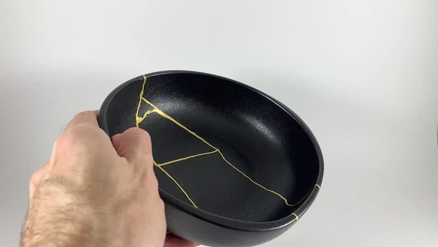 The making of kintsugi, artisan making kintsugi process. Slow motion cinematic video. Black Kintsukuroi bowl.
Closeup isolated.